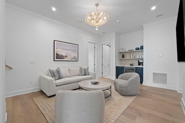 living room with bar, ornamental molding, a chandelier, and light wood-type flooring