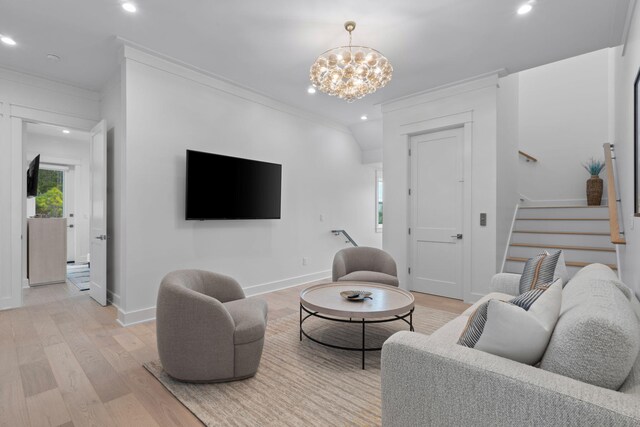 living room featuring crown molding, a chandelier, and light wood-type flooring