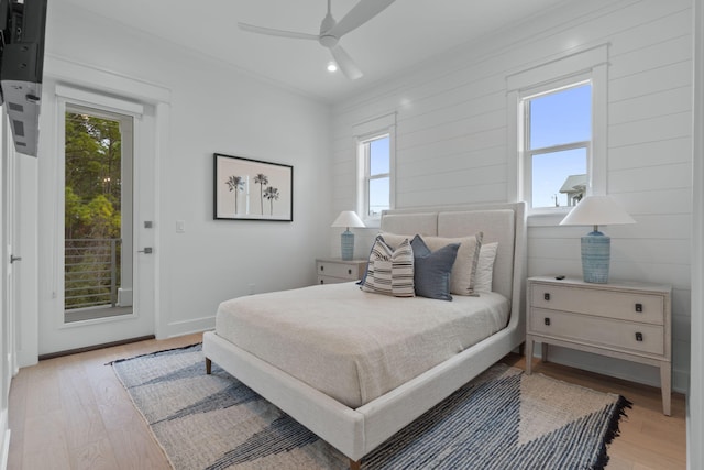 bedroom with multiple windows, ornamental molding, access to exterior, and light wood-type flooring