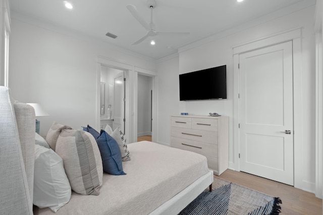 bedroom featuring ornamental molding, ensuite bathroom, ceiling fan, and light wood-type flooring