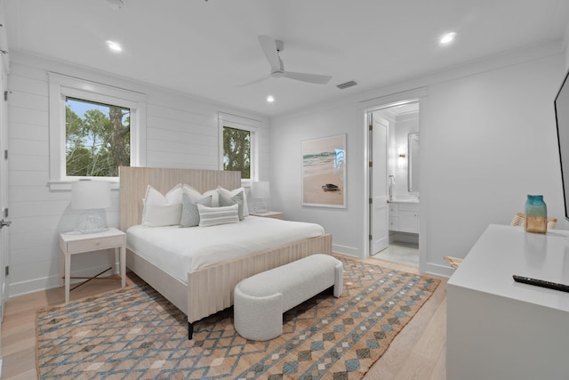 bedroom with multiple windows, hardwood / wood-style flooring, ornamental molding, and ensuite bathroom