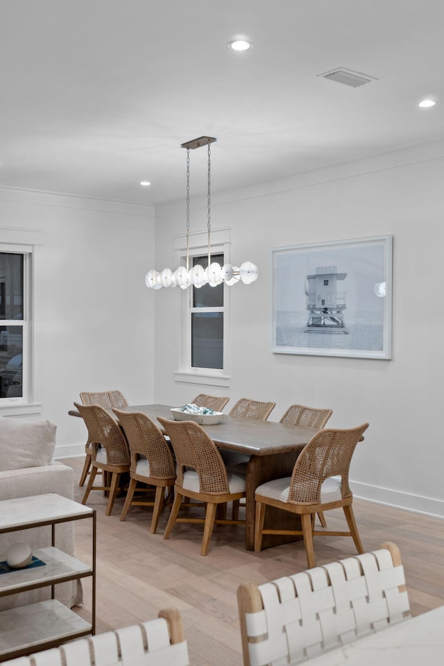 dining space with crown molding and light hardwood / wood-style floors