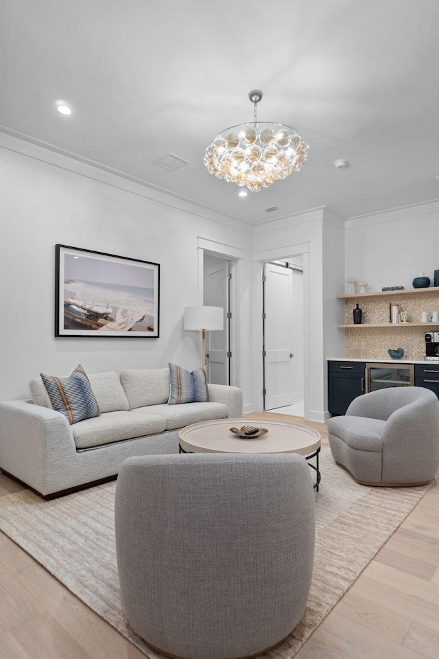 living room featuring crown molding, a chandelier, and light wood-type flooring