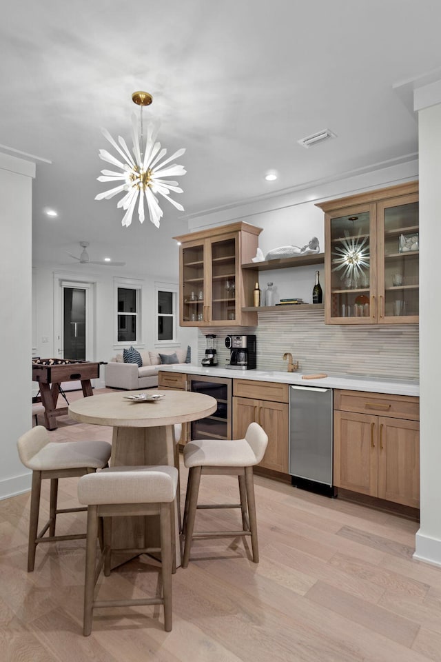 kitchen with wine cooler, a chandelier, light hardwood / wood-style flooring, pendant lighting, and backsplash