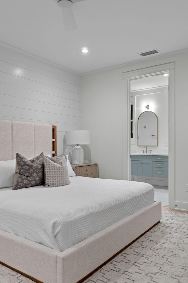 bedroom with ornamental molding, ensuite bathroom, and sink