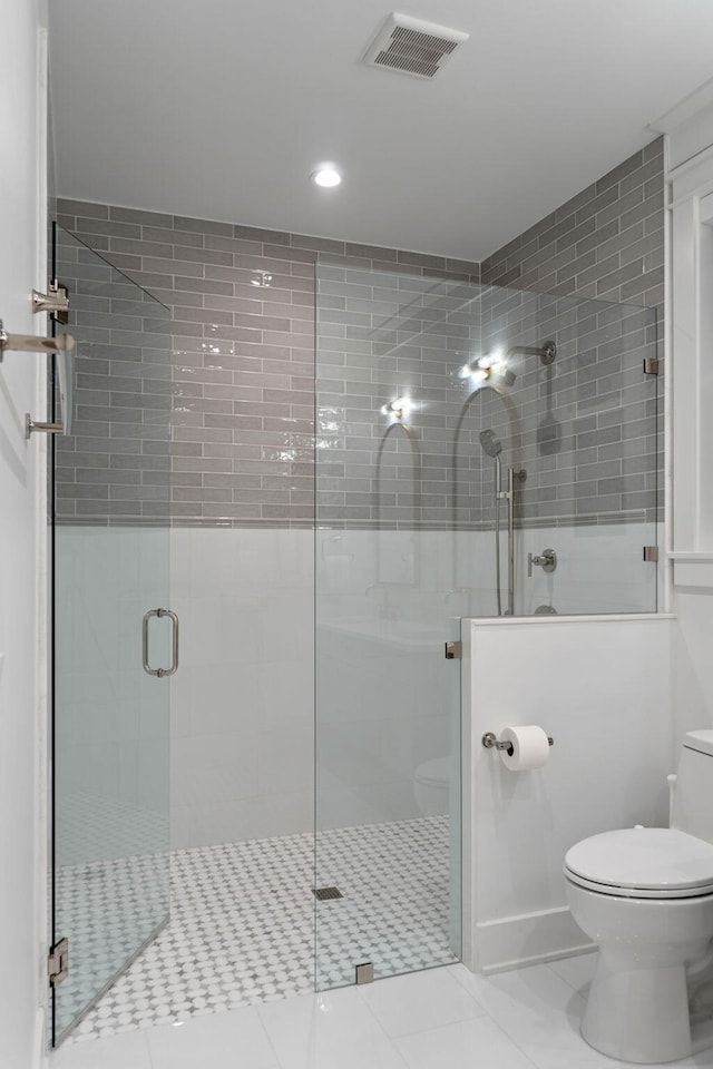 bathroom with tile patterned flooring, toilet, and walk in shower