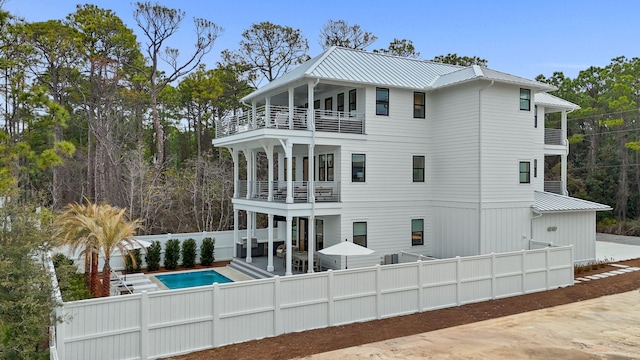 rear view of property featuring a fenced in pool, a patio area, and a balcony