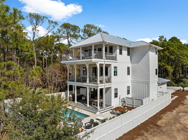 back of property featuring a balcony, outdoor lounge area, a fenced in pool, and a patio area