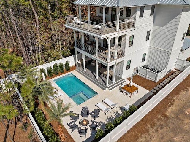 back of house with a fenced in pool, a balcony, a patio area, and a fire pit