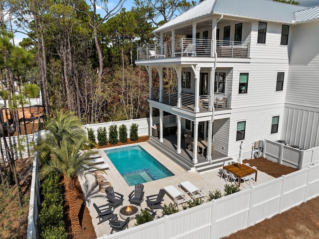 back of property featuring a fenced in pool, a patio area, a balcony, and an outdoor fire pit