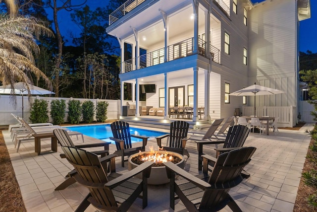 91 Pelayo Ave, Santa Rosa Beach, FL 32459 - patio at night with a balcony, french doors, a fire pit, a fenced backyard, and outdoor dining space
