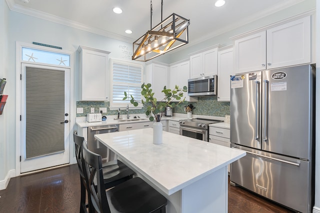 kitchen with pendant lighting, white cabinetry, sink, premium appliances, and a center island