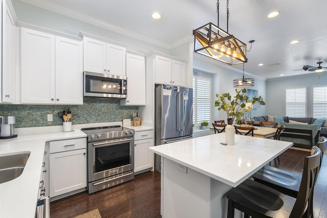 kitchen featuring white cabinetry, crown molding, hanging light fixtures, and premium appliances