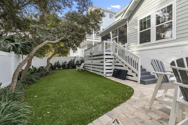 view of yard featuring a deck, a patio area, and a sunroom