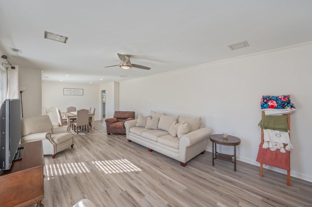 living room with crown molding, ceiling fan, and light wood-type flooring