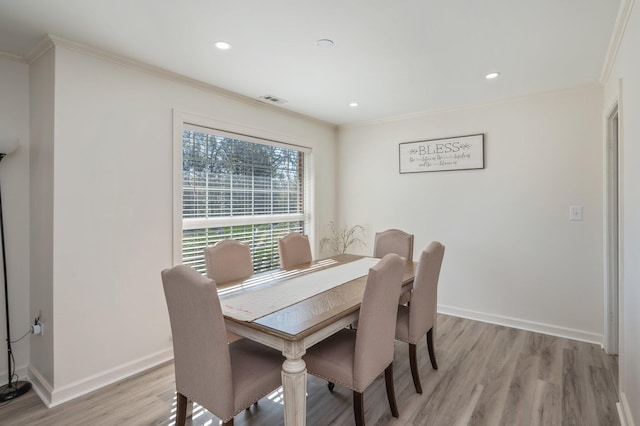 dining area featuring ornamental molding and light hardwood / wood-style flooring