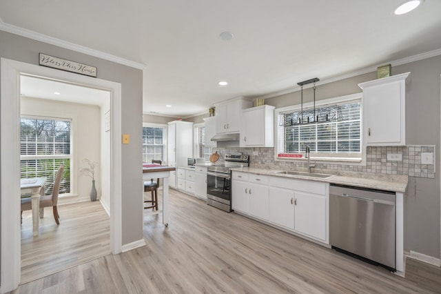 kitchen with decorative light fixtures, sink, white cabinets, stainless steel appliances, and crown molding