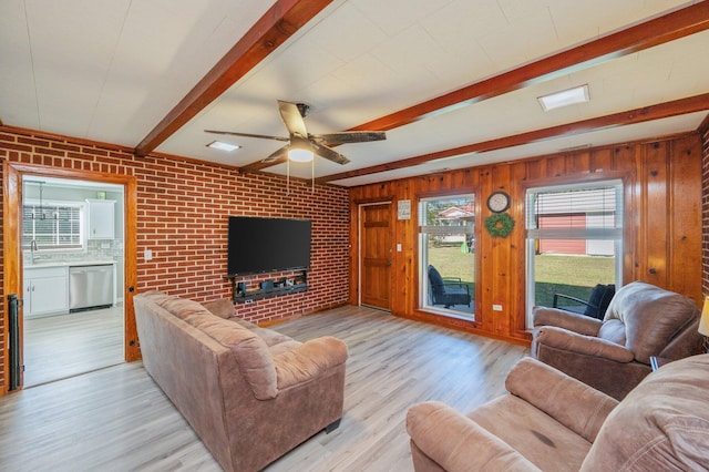 living room with ceiling fan, brick wall, beam ceiling, and light hardwood / wood-style floors