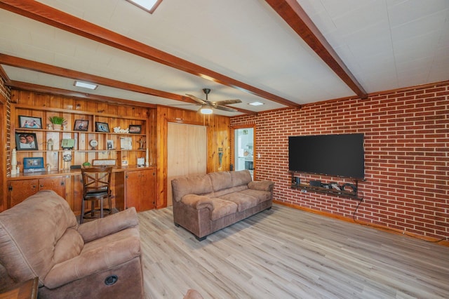 living room with ceiling fan, brick wall, beam ceiling, and light hardwood / wood-style flooring