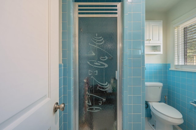 bathroom with tile walls, a shower with shower door, and toilet