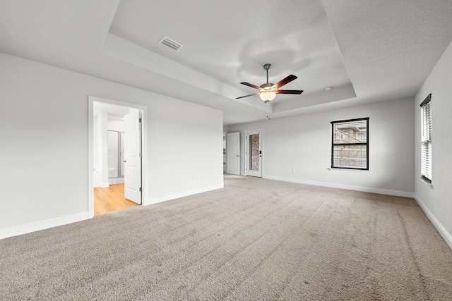 carpeted empty room featuring a raised ceiling and ceiling fan