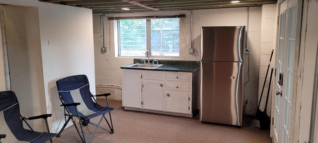 kitchen featuring stainless steel fridge, sink, and white cabinets