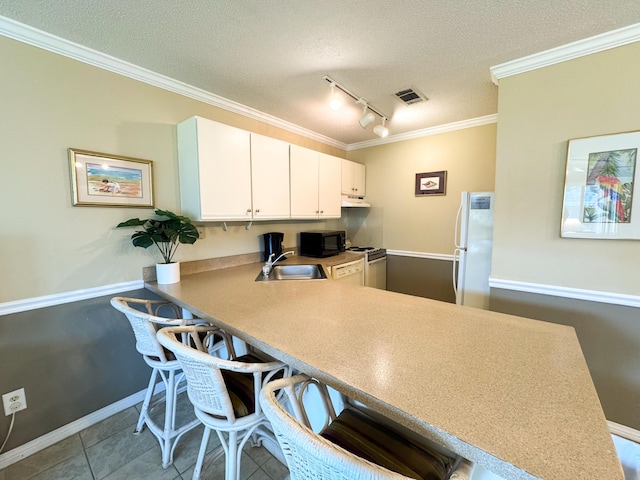 kitchen featuring sink, white refrigerator, a kitchen breakfast bar, kitchen peninsula, and white cabinets