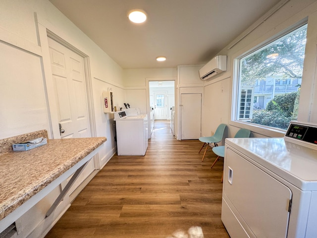 laundry room featuring a wall mounted air conditioner, hardwood / wood-style floors, and washer and dryer