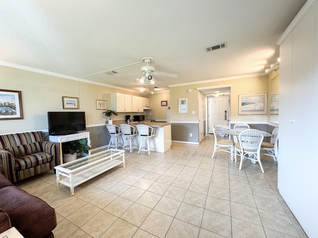 living room featuring crown molding, ceiling fan, a textured ceiling, and light tile patterned floors