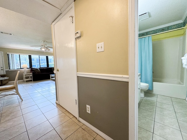 corridor with light tile patterned floors, ornamental molding, and a textured ceiling