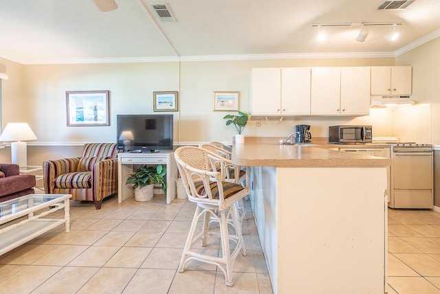 kitchen featuring a kitchen bar, light tile patterned floors, ornamental molding, white range, and white cabinets