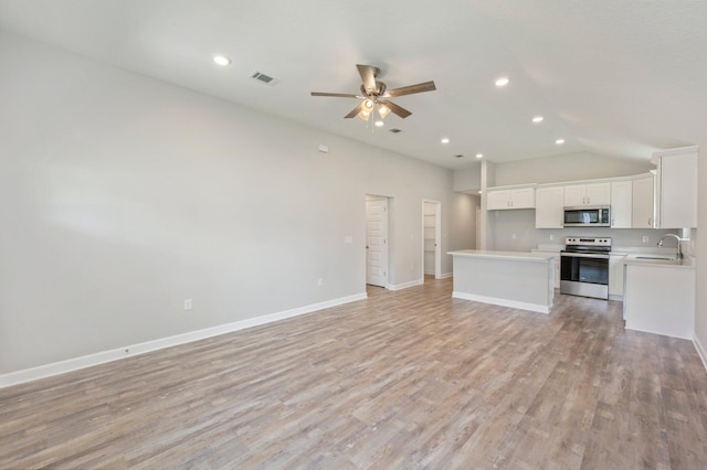 unfurnished living room featuring visible vents, baseboards, light wood-style floors, a ceiling fan, and a sink