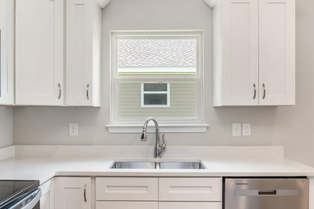 kitchen with stainless steel dishwasher, light countertops, white cabinetry, and a sink