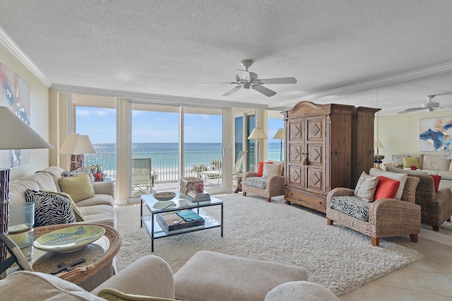 living room with a water view, light tile patterned floors, ceiling fan, ornamental molding, and a wall of windows