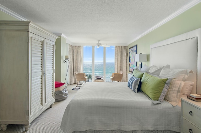 carpeted bedroom with ornamental molding, expansive windows, a textured ceiling, and a water view