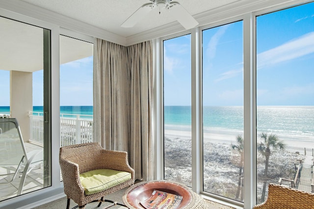 sitting room with a water view, a beach view, and crown molding