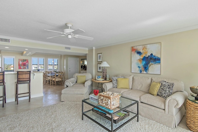 living room with ceiling fan, ornamental molding, tile patterned flooring, and a textured ceiling