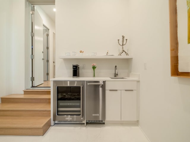 bar with white cabinetry, sink, and beverage cooler