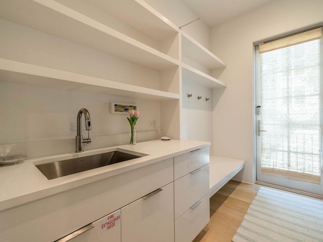 interior space with sink, hookup for a washing machine, light hardwood / wood-style floors, and a healthy amount of sunlight