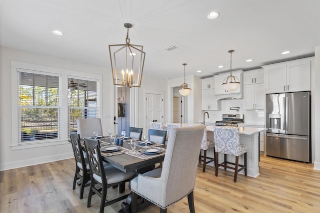 dining area with an inviting chandelier, sink, and light wood-type flooring