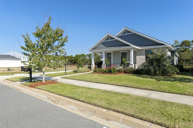 craftsman inspired home featuring a porch and a front lawn