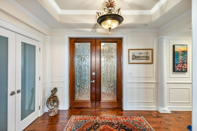 entryway with dark wood-type flooring, a tray ceiling, ornamental molding, french doors, and ornate columns