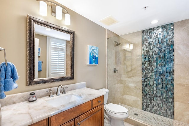 bathroom featuring vanity, toilet, and a tile shower