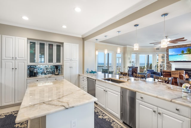 kitchen featuring sink, ornamental molding, pendant lighting, light stone countertops, and white cabinets