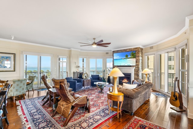 living room with ornamental molding, dark hardwood / wood-style floors, ceiling fan, and a fireplace