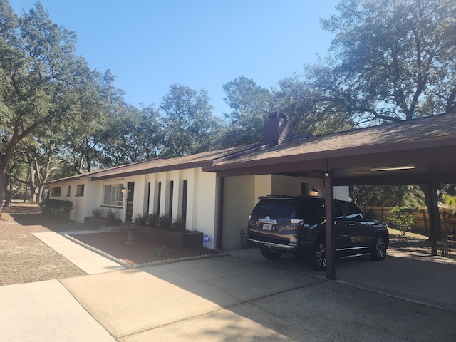 view of front facade featuring driveway, an attached carport, and fence