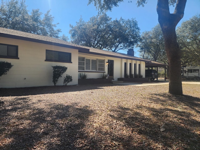 rear view of house with an attached carport and a chimney