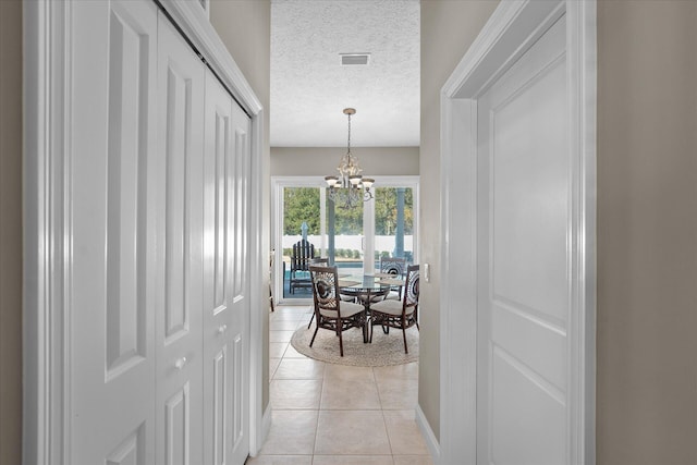 dining space featuring an inviting chandelier, light tile patterned floors, and a textured ceiling