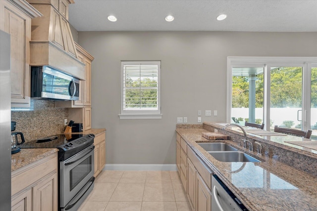 kitchen featuring appliances with stainless steel finishes, sink, decorative backsplash, light tile patterned floors, and light stone counters