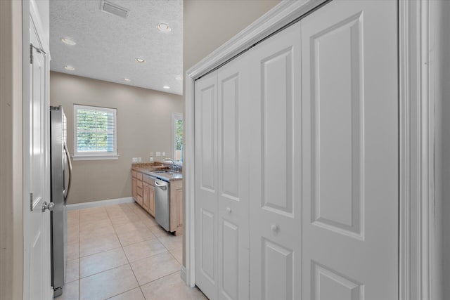 kitchen featuring light tile patterned floors, stainless steel appliances, sink, and a textured ceiling